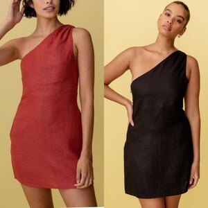 May include: Two women wearing one-shoulder linen dresses. The dress on the left is a rust color and the dress on the right is black.