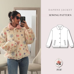 Op de afbeelding: Een crèmekleurige jas met een roze kraag en bloemenpatroon. De jas heeft een knoopsluiting aan de voorkant en lange mouwen. De afbeelding bevat ook een naaipatroondiagram en de tekst "DAPHNE JACKET SEWING PATTERN".