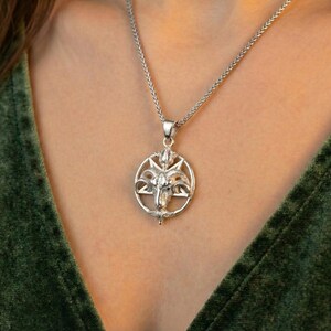 A silver pendant necklace with a circular design on the front.