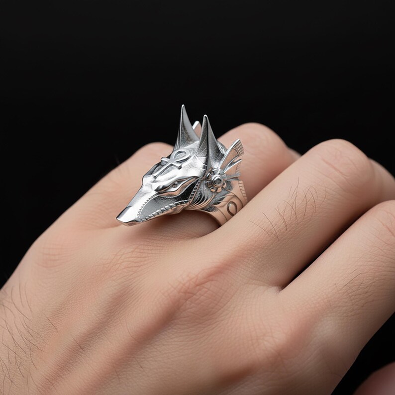 A close-up image of a person's hand wearing a silver ring in the shape of a fox's head.