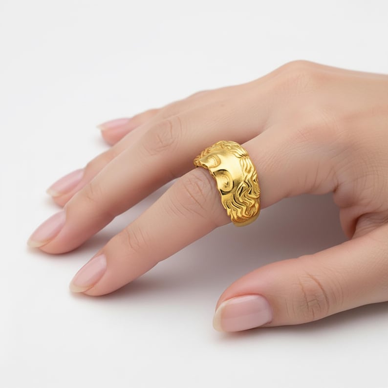 A close-up of a hand wearing a gold ring with an intricate design.