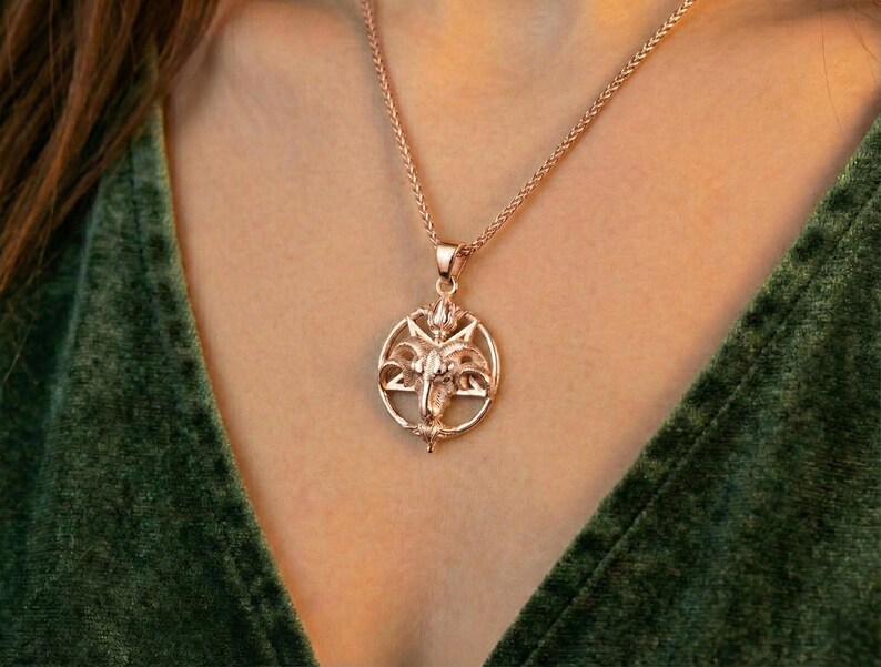 A close-up of a person wearing a gold-colored pendant necklace with a circular design.