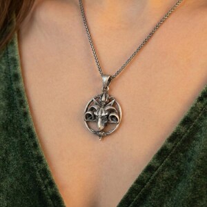 A silver pendant necklace with a circular design on the front.