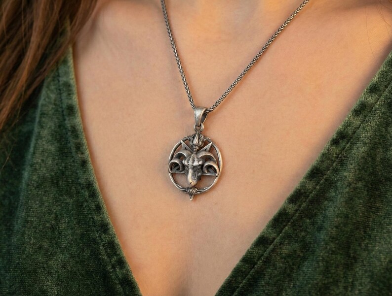 A silver pendant necklace with a circular design on the front.