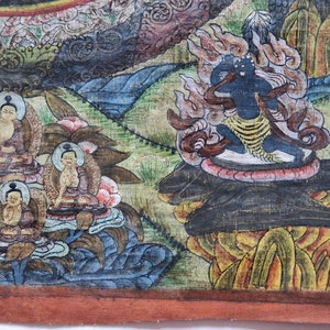 Pu&ograve; includere: Un dipinto buddista tibetano colorato che raffigura una divinit&agrave; circondata da fiamme, seduta su un trono di loto. La divinit&agrave; &egrave; nera con una fascia gialla ed &egrave; circondata da un gruppo di figure pi&ugrave; piccole.