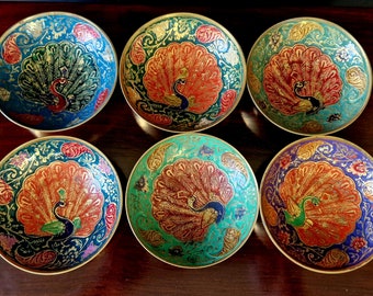 May include: Six brass bowls with intricate peacock designs. Each bowl features a different colour scheme, including blue, green, orange, and purple.