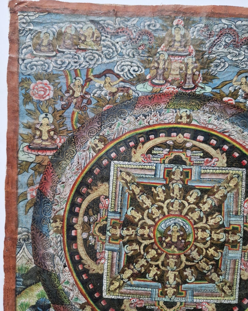 Pu&ograve; includere: Un dipinto di mandala colorato su tela con dettagli intricati e una figura centrale. Il dipinto presenta un design circolare con un quadrato al centro, circondato da cerchi pi&ugrave; piccoli e figure. I colori sono vivaci e includono rosso, blu, verde, giallo e oro.