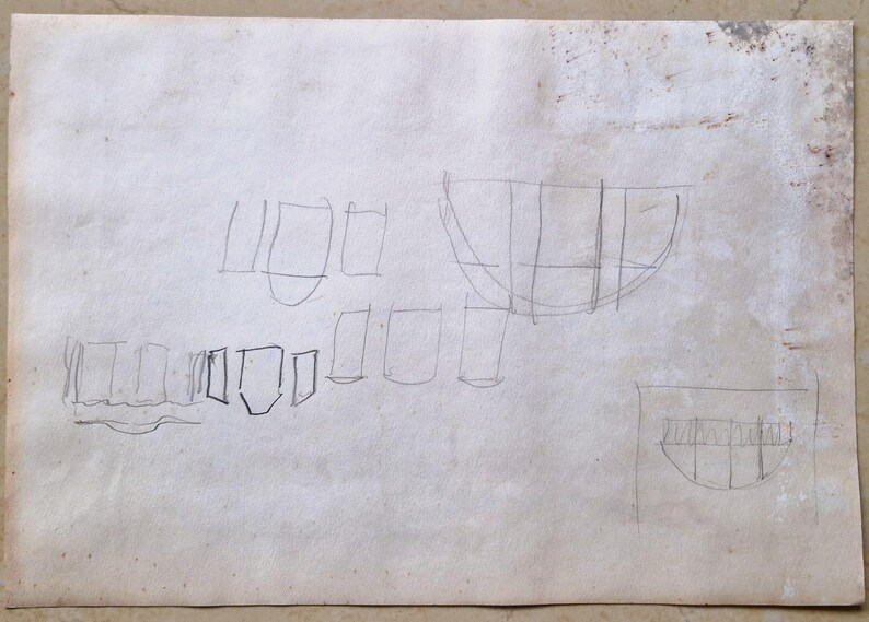 Puede incluir: Un boceto dibujado a mano en papel blanco con varias formas geom&eacute;tricas, incluyendo rect&aacute;ngulos, cuadrados y una forma curva que se asemeja a un barco.