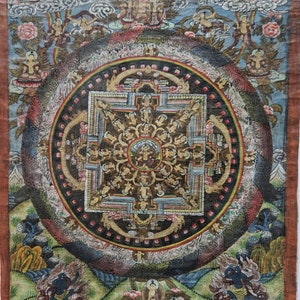 Pu&ograve; includere: Un dipinto di mandala colorato su tela che rappresenta un disegno circolare con pi&ugrave; figure e dettagli intricati. Il mandala &egrave; circondato da un bordo di fiori e foglie, e lo sfondo &egrave; un cielo blu con nuvole.