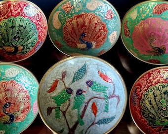 May include: Set of six brass bowls with intricate hand-painted designs featuring peacocks and floral motifs. The bowls are in shades of red, green, blue, and gold.