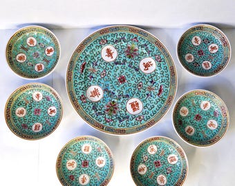 May include: A set of seven Chinese porcelain bowls and a large plate with a turquoise blue background and intricate floral and scroll designs. The bowls and plate feature red Chinese characters.
