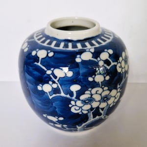 Könnte beinhalten: Eine kleine blaue und weiße Porzellanvase mit Blumenmuster. Die Vase hat einen runden Körper und einen schmalen Hals. Das Blumenmuster ist in Weiß auf blauem Hintergrund.