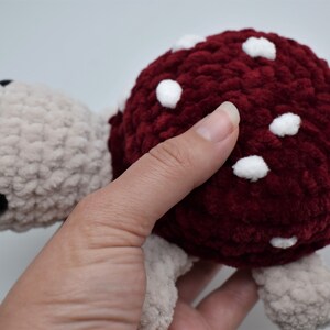 May include: A handmade plush turtle toy. The turtle has a burgundy shell with white spots and a light beige head, feet, and tail. The toy is made of a soft, textured material.