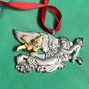 May include: Silver angel Christmas ornament with a gold bird and a red ribbon.