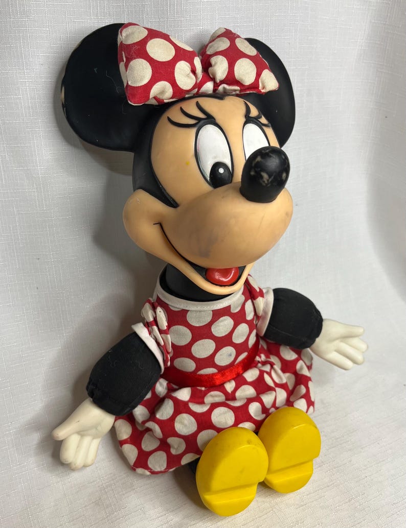 Peut inclure: Figurine de Minnie Mouse, avec une t&ecirc;te et des oreilles noires, un n&oelig;ud &agrave; pois rouges et blancs, et une robe assortie. La figurine a des chaussures jaunes et des gants blancs. Le design est une repr&eacute;sentation classique du personnage de dessin anim&eacute; bien-aim&eacute;.