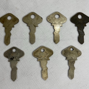 May include: Eight antique keys with different designs and finishes. The keys are made of metal and have a worn, aged appearance. Some keys have intricate details and markings.