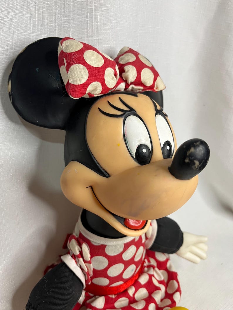 Peut inclure: Poup&eacute;e vintage de Minnie Mouse avec une t&ecirc;te et des oreilles noires, un visage bronz&eacute; et un n&oelig;ud et une robe &agrave; pois rouges et blancs. La poup&eacute;e a des gants blancs et un nez noir. Un personnage classique de Disney.