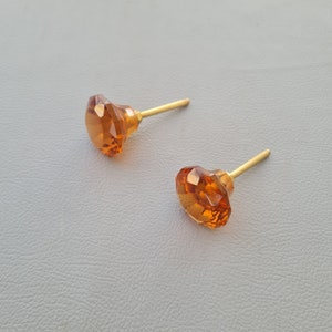 Puede incluir: Dos pomos de armario de vidrio ámbar con tallos de metal dorado. Los pomos son facetados y tienen forma de diamante.