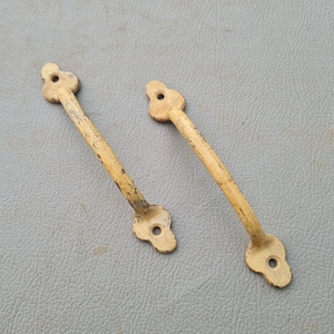 May include: Two antique yellow metal door handles with ornate designs. The handles are made of metal and have a worn, aged look.
