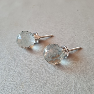 Può includere: Due pomelli per armadi in vetro trasparente con un design sfaccettato e steli in metallo argentato.