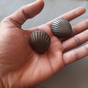 May include: Two silver-colored metal shell-shaped buttons with a ribbed design.