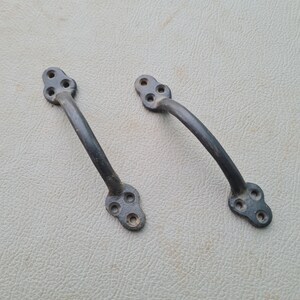 May include: Two black metal door handles with a decorative, three-hole design.