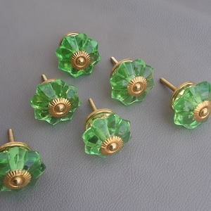 May include: Six green glass cabinet knobs with gold metal accents. Each knob has a starburst design.