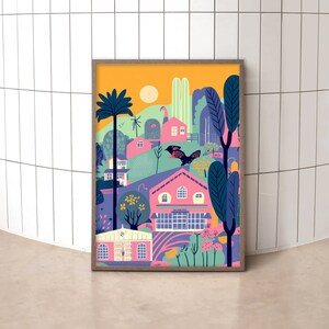 May include: A framed illustration of a colorful, whimsical town with pink houses, green trees, and a yellow sky. The illustration features a bird flying over the town.