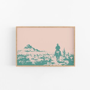 Op de afbeelding: Een turquoise silhouet van een cowboy die op een paard door een woestijnlandschap met een roze lucht rijdt. De cowboy draagt een hoed en het paard galoppeert. Er zijn cactussen en bergen op de achtergrond.