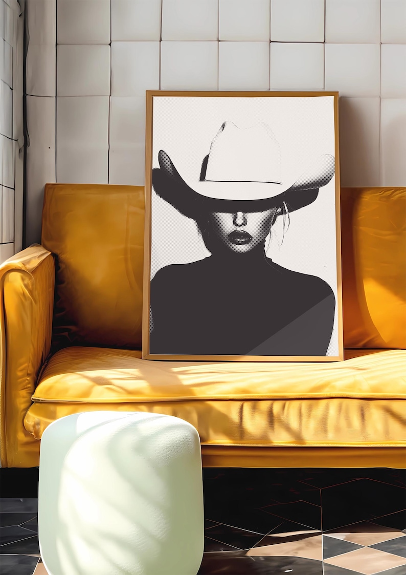 May include: Black and white photograph of a woman wearing a large white cowboy hat. The woman is looking directly at the camera. The background is a white wall.