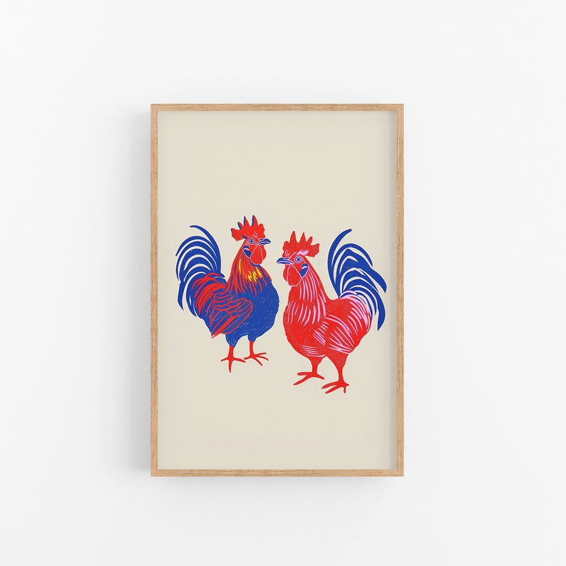 Op de afbeelding: Een ingelijste print van twee hanen, een blauwe en een rode, met hun koppen naar elkaar gekeerd. De hanen zijn gestileerd en hebben een grafische esthetiek.