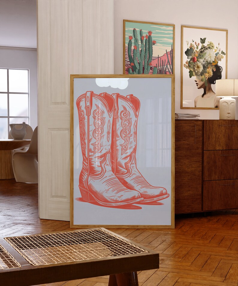 May include: A framed print of two red cowboy boots with intricate designs on a light blue background.