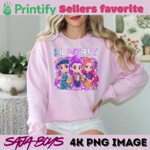 May include: A light pink sweatshirt featuring the word "HUNTRIX" above a graphic of three cartoon characters. The sweatshirt also has the text "Printify Sellers favorite" and "SATA BOYS 4K PNG IMAGE".