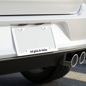 May include: A white car with a license plate that reads "hot girls do lashes".