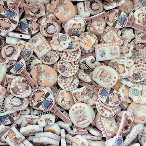 May include: A collection of various beige and brown Dimoo charms. The charms feature cartoon characters, some with the word "Dimoo" printed on them. The shapes include circles, paddles, and other decorative forms. The overall theme is cute and playful.