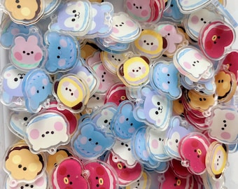 May include: A collection of small, clear acrylic charms featuring various cartoon animal faces in colors including pink, blue, yellow, and red. Each charm has a smooth, glossy finish and a small hole at the top for attachment, arranged in a pile.