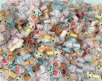 May include: A large collection of small, clear acrylic charms shaped like light sticks, each featuring a colorful cartoon character face. The charms include various pastel and bright colors like yellow, blue, pink, and red, with small loops for attachment.