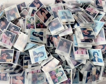 May include: A large collection of square, white-bordered plastic photo frames, each containing a unique portrait of a person. The frames are scattered in a pile, and each one features the word NORMAL printed in black text at the bottom.