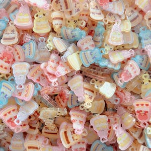 May include: A collection of pastel-colored acrylic charms in various shapes, including cakes, bears, and desserts. The charms are in shades of pink, blue, yellow, and white, with a glossy finish. These charms are ideal for jewelry making or crafting projects.