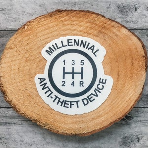 May include: White sticker with black text and a gear shift pattern. The text reads "Millennial Anti-theft Device".