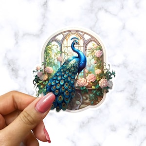 May include: A blue and green peacock with its tail feathers spread out stands in a window with pink roses and green vines. The window is arched and has a stone frame.