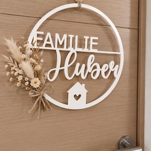 3D gedrucktes personalisiertes Türschild in weiß mit beigen Trockenblumen an einer braunen Innentür.