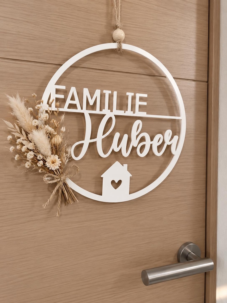 3D gedrucktes personalisiertes Türschild in weiß mit beigen Trockenblumen an einer braunen Innentür.