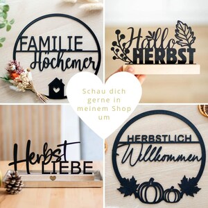 Op de afbeelding: Een collectie zwarte, lasergesneden borden met Duitse tekst, waaronder FAMILIE H&Ouml;CHEMER, Hallo HERBST, Herbst LIEBE en HERBSTLICH Willkommen, voorzien van decoratieve elementen zoals een huis, bladeren en pompoenen.