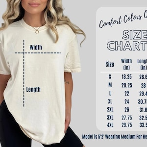 May include: Cream-colored t-shirt with a size chart. The chart lists sizes S to 4XL, with width and length measurements in inches. The text "Comfort Colors C1717" is at the top. The model is wearing a medium.