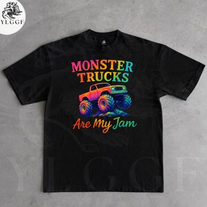 May include: Black t-shirt with a colorful graphic of a monster truck and the text "MONSTER TRUCKS Are My Jam". The monster truck is orange, pink, and blue with large, multi-colored tires. The text is in rainbow colors.