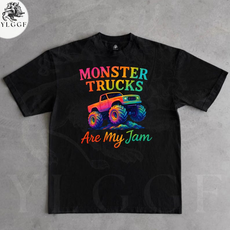 May include: Black t-shirt with a colorful graphic of a monster truck and the text "MONSTER TRUCKS Are My Jam". The monster truck is orange, pink, and blue with large, multi-colored tires. The text is in rainbow colors.