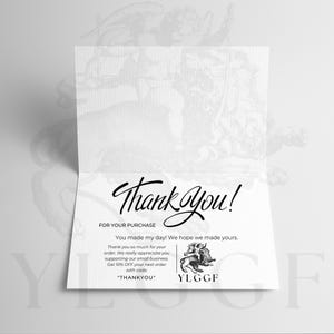 May include: A folded white card with the words "Thank You!" in elegant script. The card includes text expressing gratitude for a purchase and a discount code for future orders. A small illustration of a winged creature is also present.