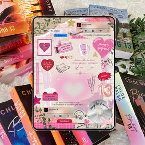 K&ouml;nnte beinhalten: Eine transparente Tablet-H&uuml;lle mit einem rosa-wei&szlig;en Collage-Design mit Herzen, Sternen und Text. Die H&uuml;lle ist von B&uuml;chern mit Titeln wie "Binding 13" und "Keeping 13" von Chloe Walsh umgeben. Das Design enth&auml;lt die Zahl "13".