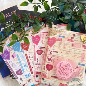 May include: A collection of book covers featuring a collage of pink, red, and blue graphics, including hearts, text snippets, and illustrations. The designs incorporate phrases like Hopeless Romantic, song titles, and various icons layered over grid patterns and paper textures.